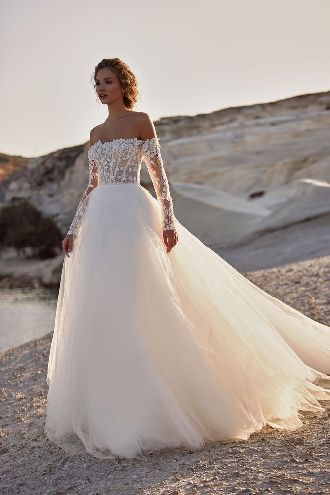 Eine Frau trägt ein weißes Brautkleid mit langen Ärmeln.