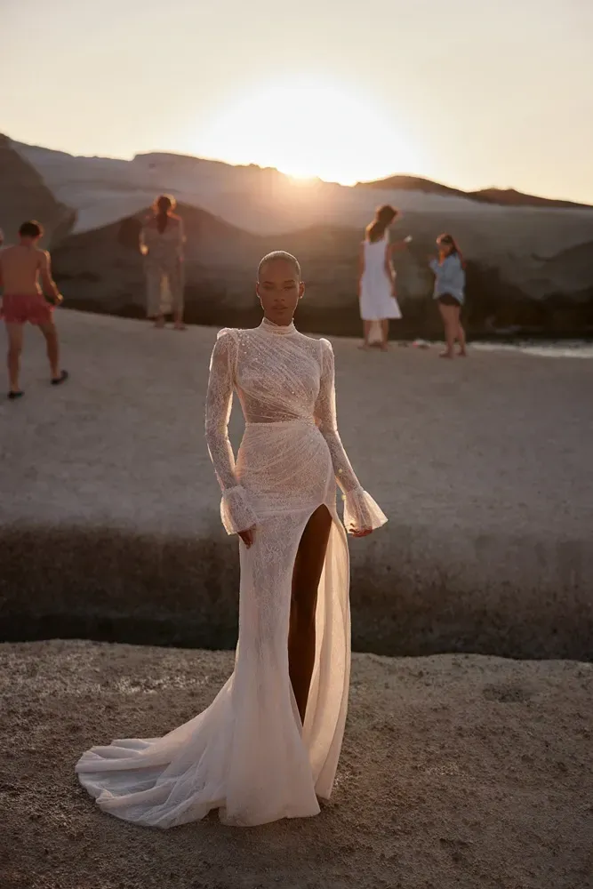 Eine Frau in einem Brautkleid steht bei Sonnenuntergang an einem Strand.
