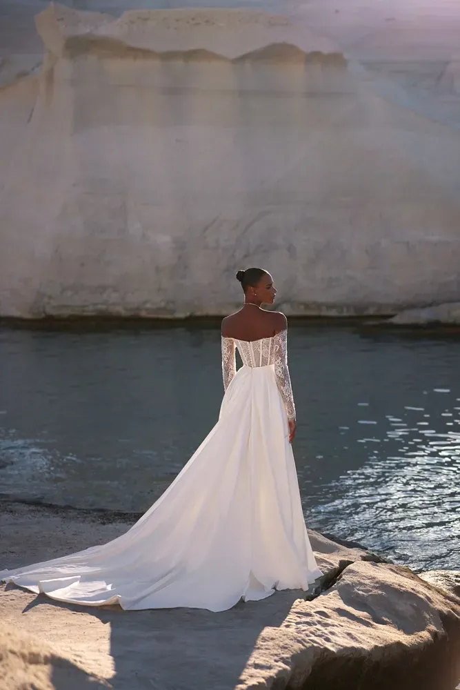 Eine Frau in einem Brautkleid steht auf einem Felsen in der Nähe des Wassers.