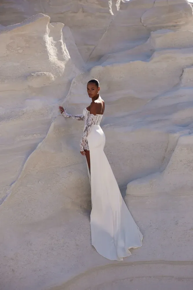 Eine Frau in einem weißen Kleid steht auf einem Felsen in der Wüste.