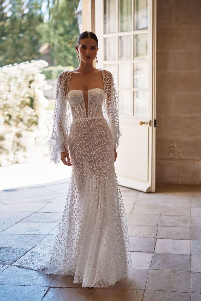 Eine Frau in einem weißen Brautkleid steht vor einer Tür.