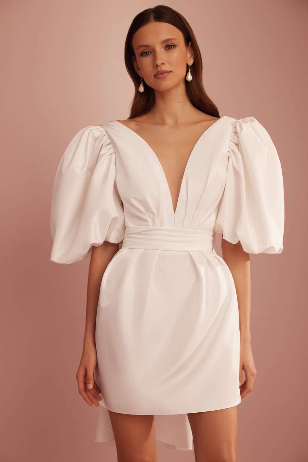 Eine Frau trägt ein weißes Kleid mit Puffärmeln und tiefem Ausschnitt.