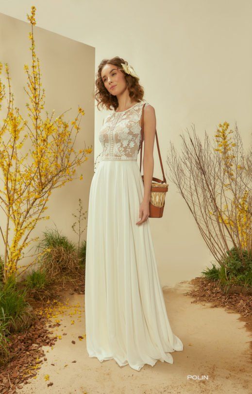 Eine Frau trägt ein weißes Brautkleid und hält eine braune Tasche.
