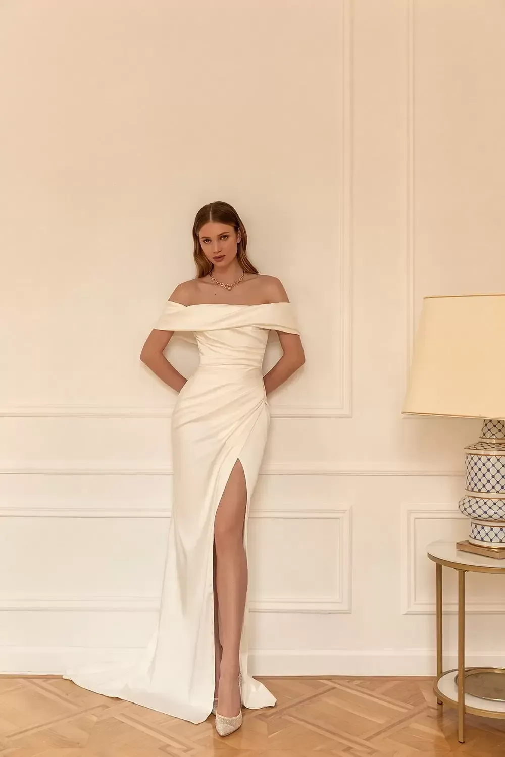 Eine Frau trägt ein weißes schulterfreies Brautkleid mit hohem Schlitz.