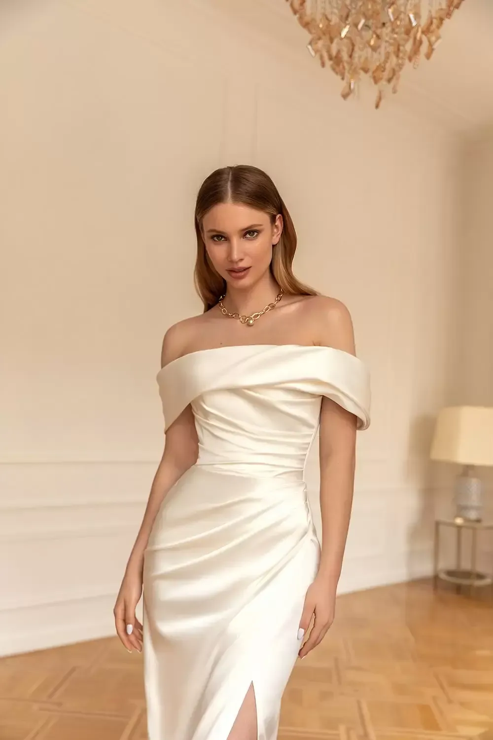 Eine Frau in einem weißen schulterfreien Brautkleid steht in einem Raum.