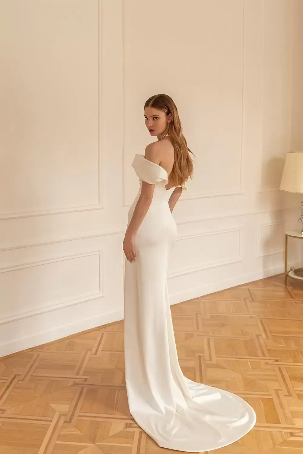 Eine Frau in einem weißen Brautkleid steht in einem Raum.