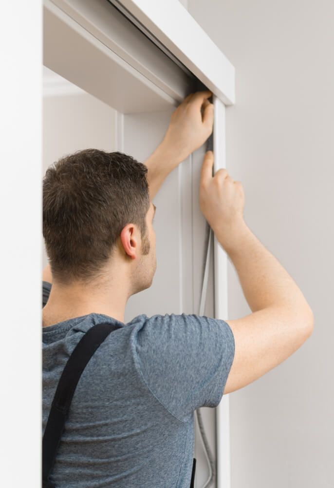 A Man Is Installing A Sliding Glass Door — Readycut Screens & Doors in Howard Springs, NT