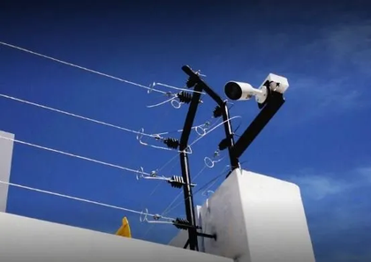Cámaras de seguridad instaladas en un poste sobre líneas eléctricas contra un cielo azul