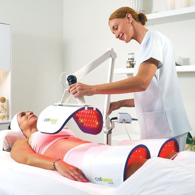 Woman receiving red light therapy on her torso and legs, administered by a technician in a spa setting.