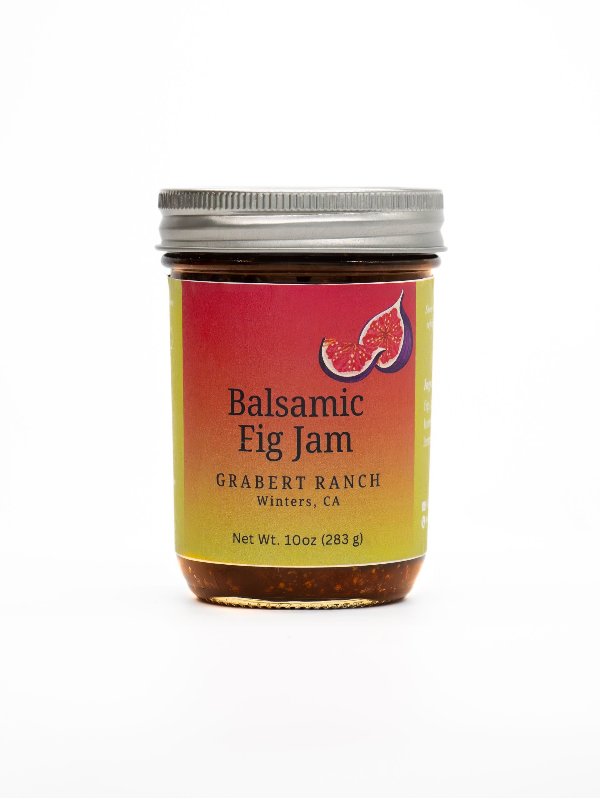 A jar of Grabert Ranch Balsamic Fig Jam with a colorful yellow to red gradient label and a silver metal lid.