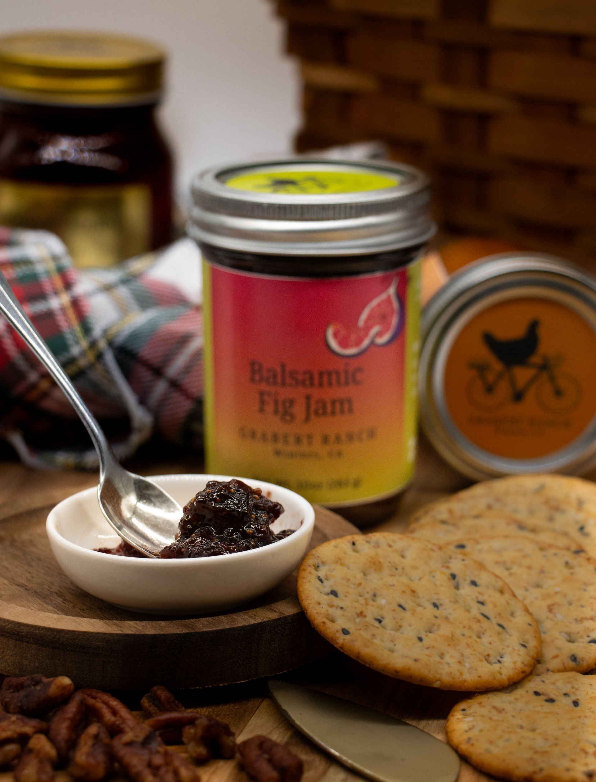 A jar of Grabert Ranch Balsamic Fig Jam with a colorful yellow to red gradient label and a silver metal lid.