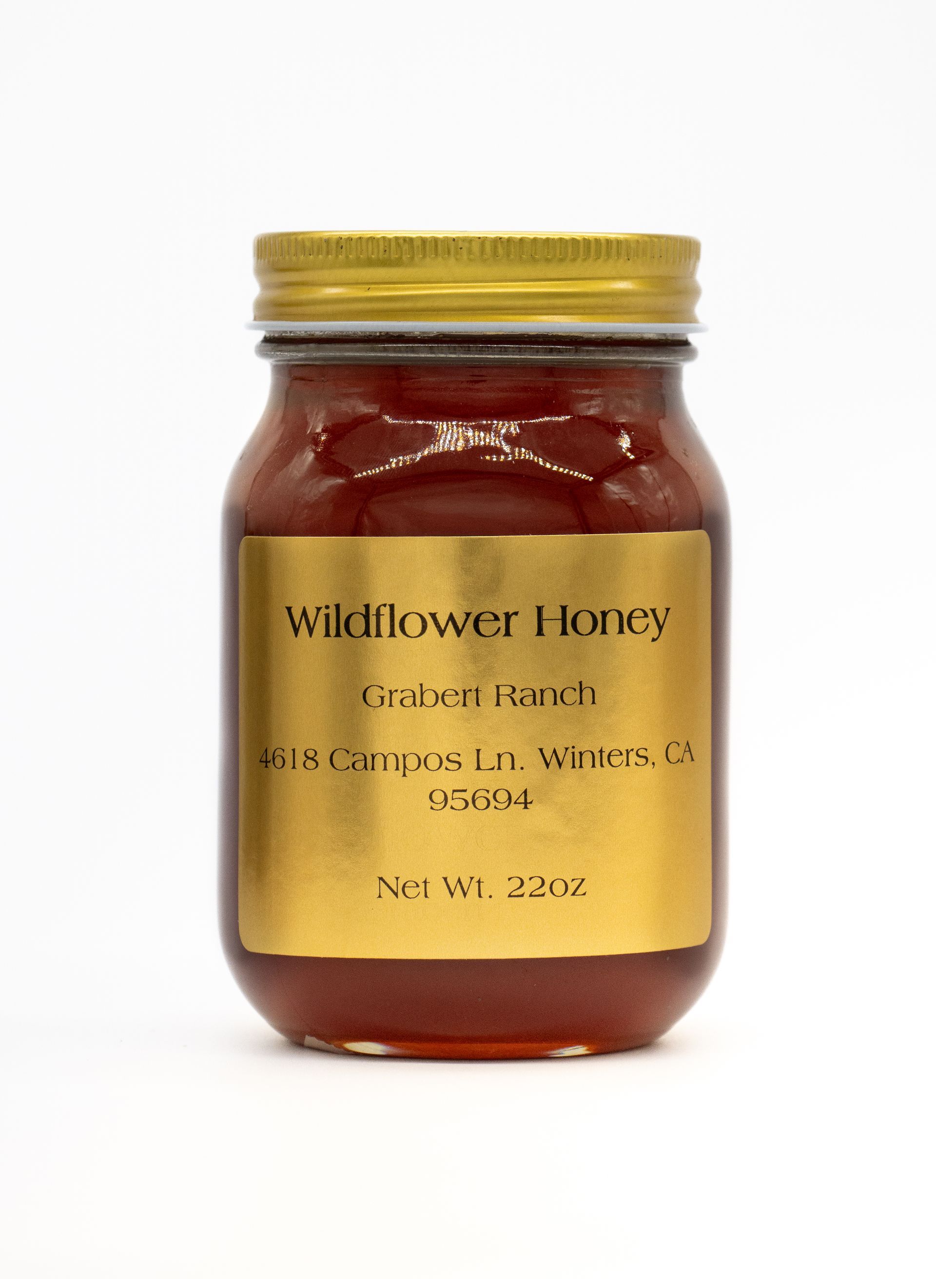 Three jars of preserves and a bowl of crackers sit on a wooden table, with a woven basket in the background.