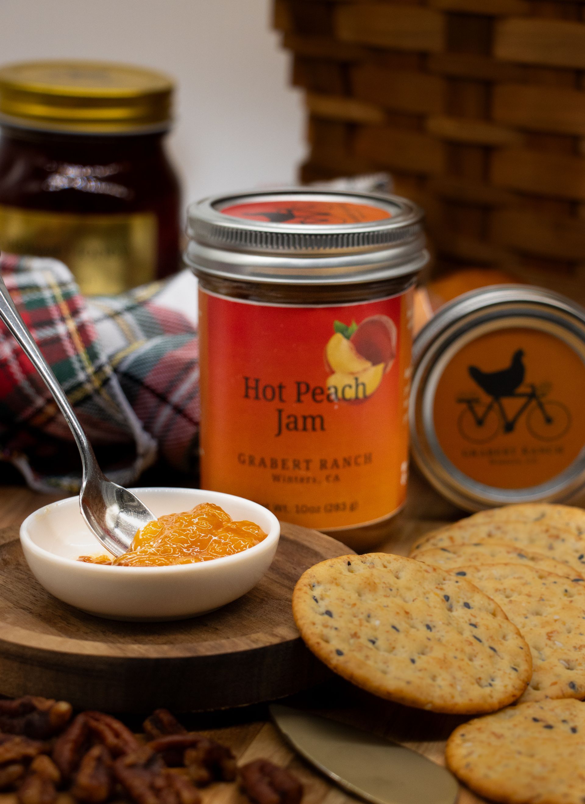 A jar of Hot Peach Jam with a silver lid and a bright orange label featuring a graphic of peaches.