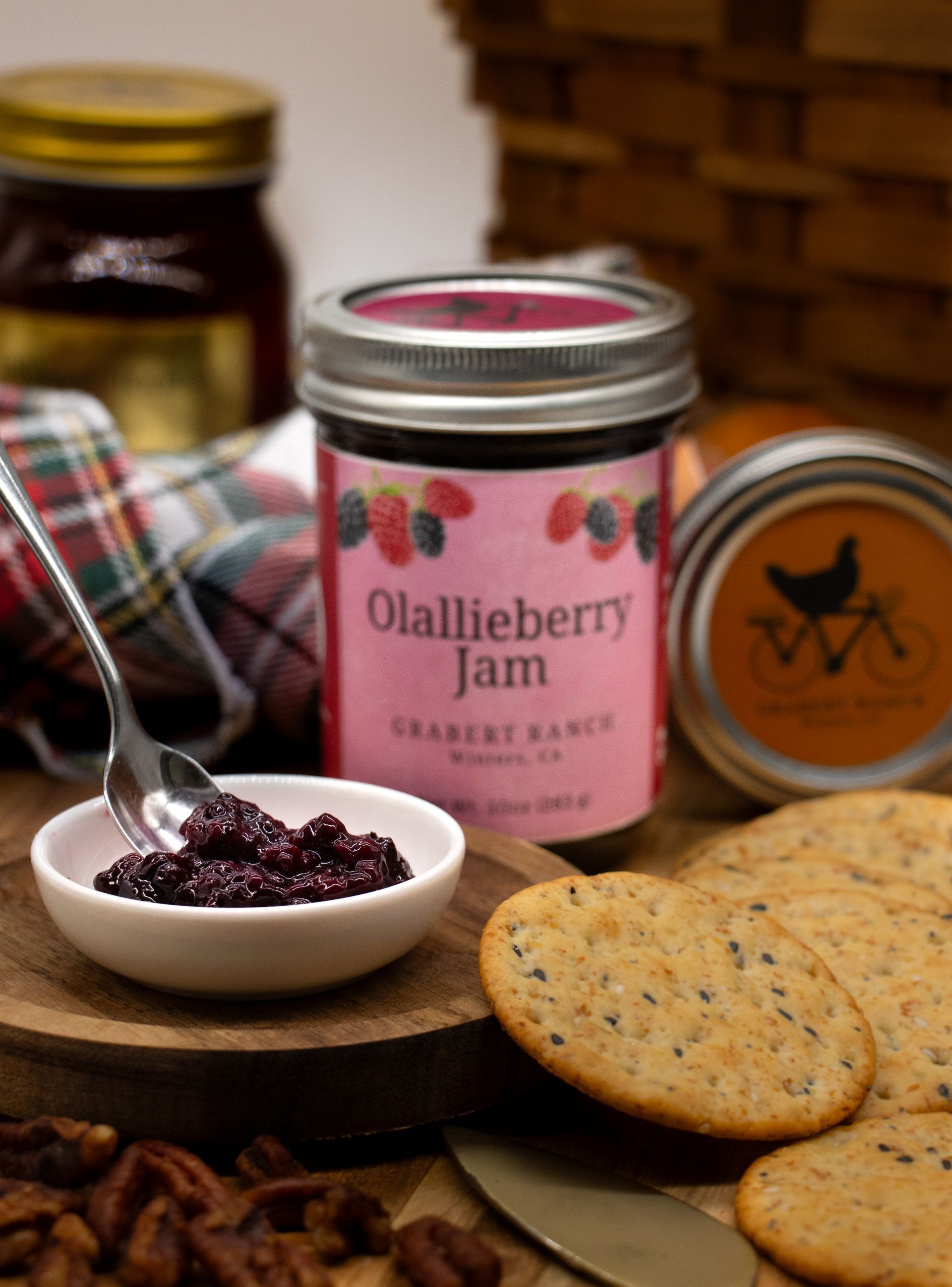A jar of Olallieberry Jam with a pink label featuring illustrations of berries, isolated against a white background.