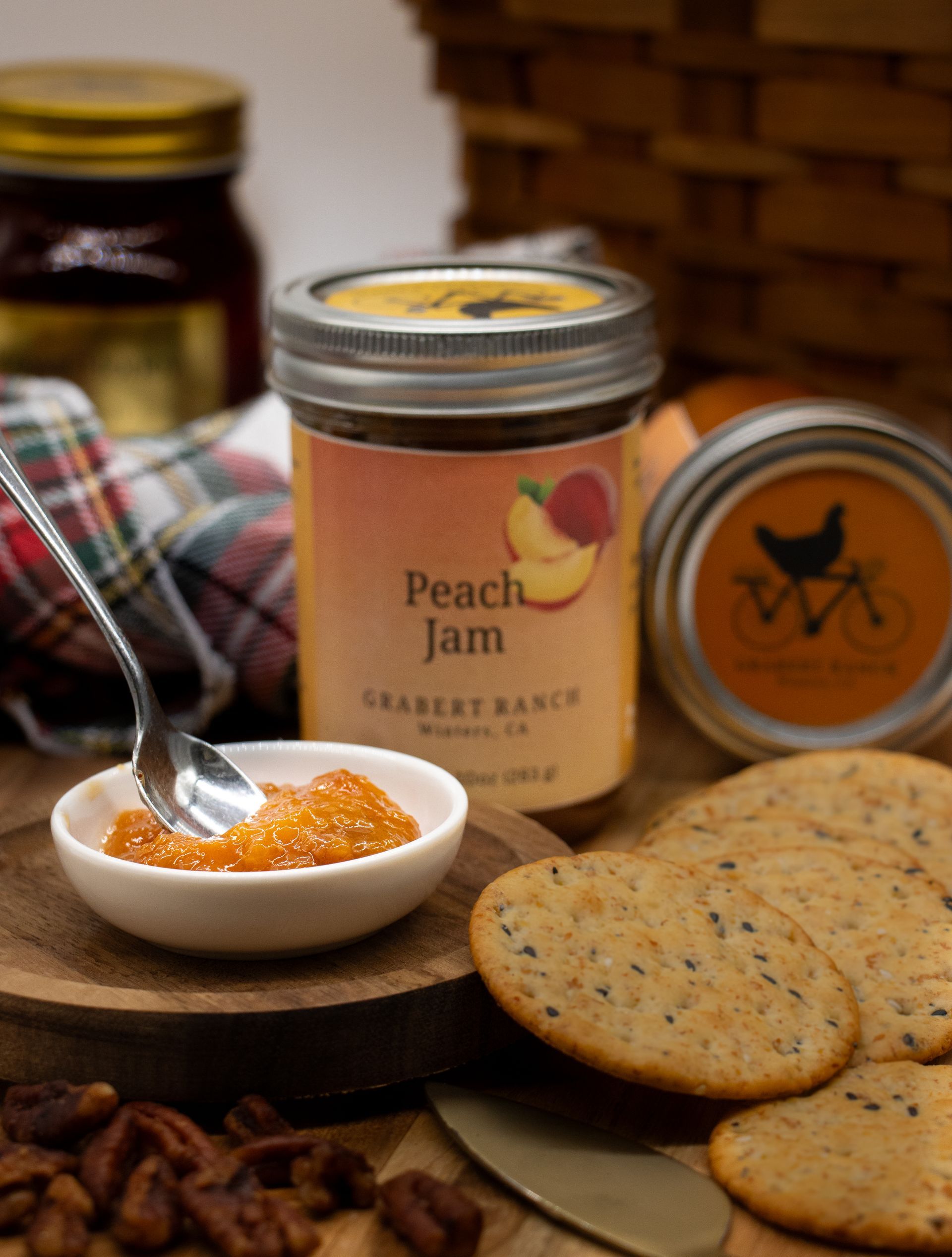 A jar of Peach Jam from Juabert Ranch with a yellow-orange label featuring an illustration of sliced peaches.