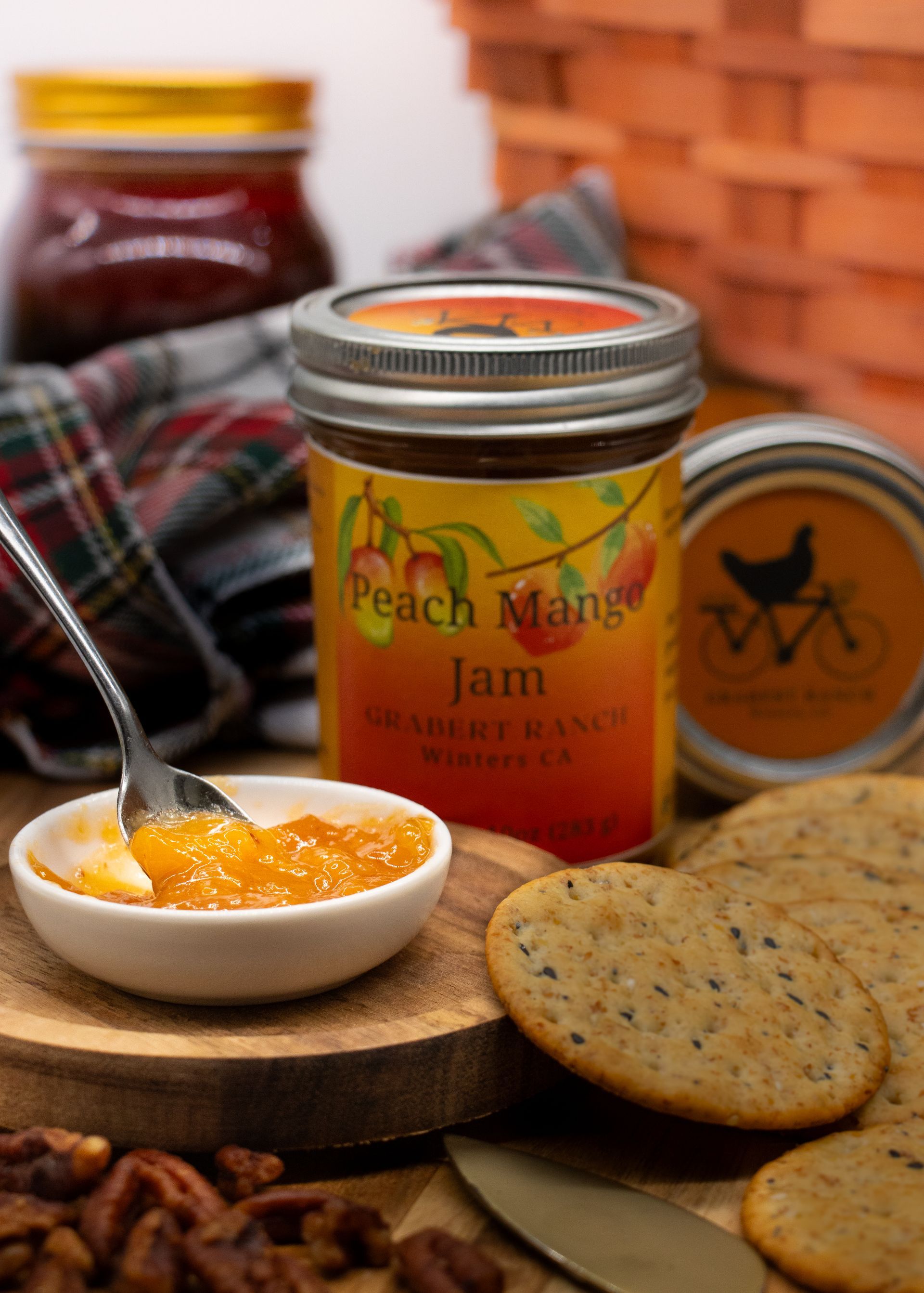 A jar of Peach Mango Jam with an orange-to-yellow label featuring an illustration of peaches and mangoes.