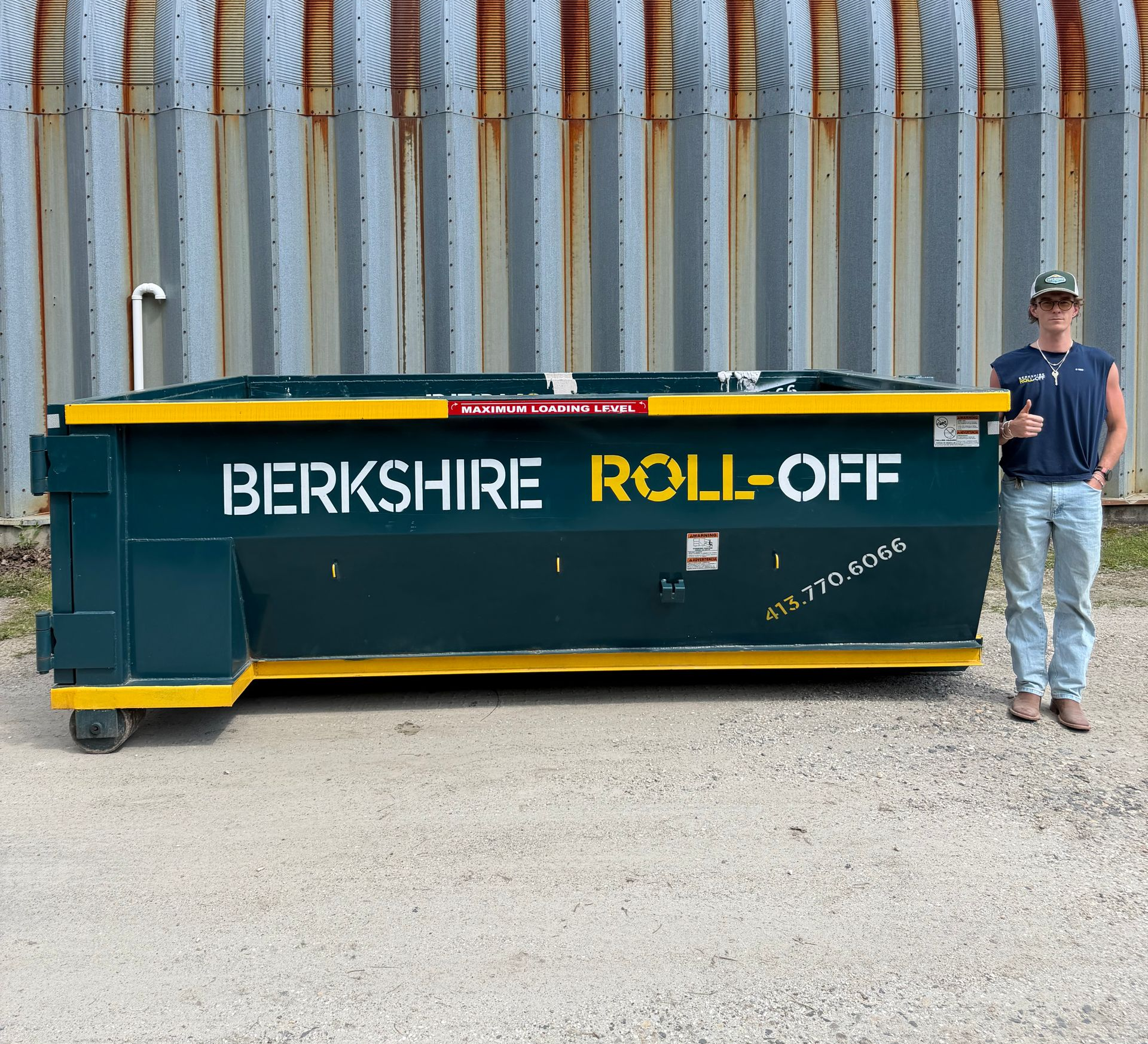 Green Berkshire roll-off dumpster with yellow lettering beside a man standing outdoors.