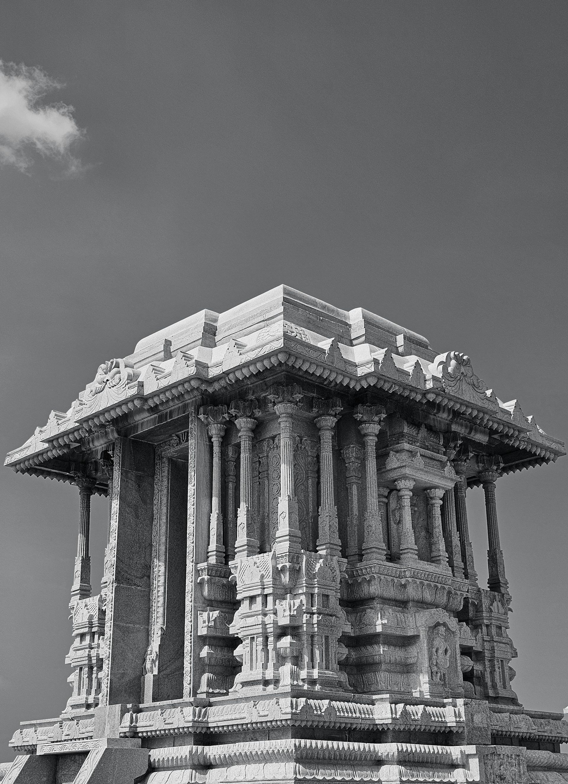 Stenen tempelwagen in Hampi, India, met gedetailleerde houtsnijwerken tegen een heldere hemel.