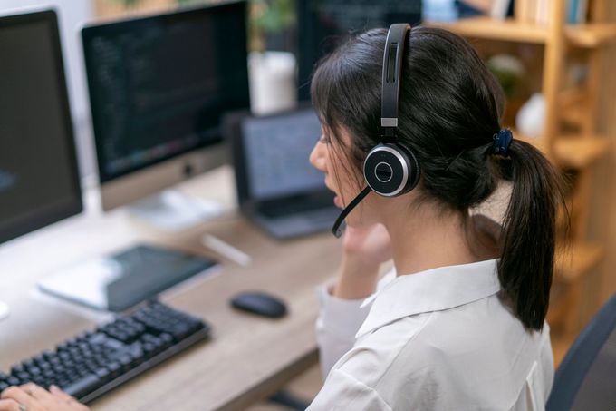 Una donna con le cuffie lavora al computer in un ufficio moderno.
