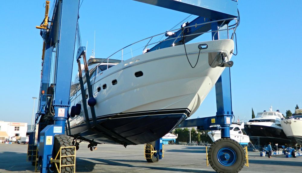 White Yacht Being Lifted by a Blue Boat Hoist — ASAP Batteries & Breakdowns in Helensvale, QLD