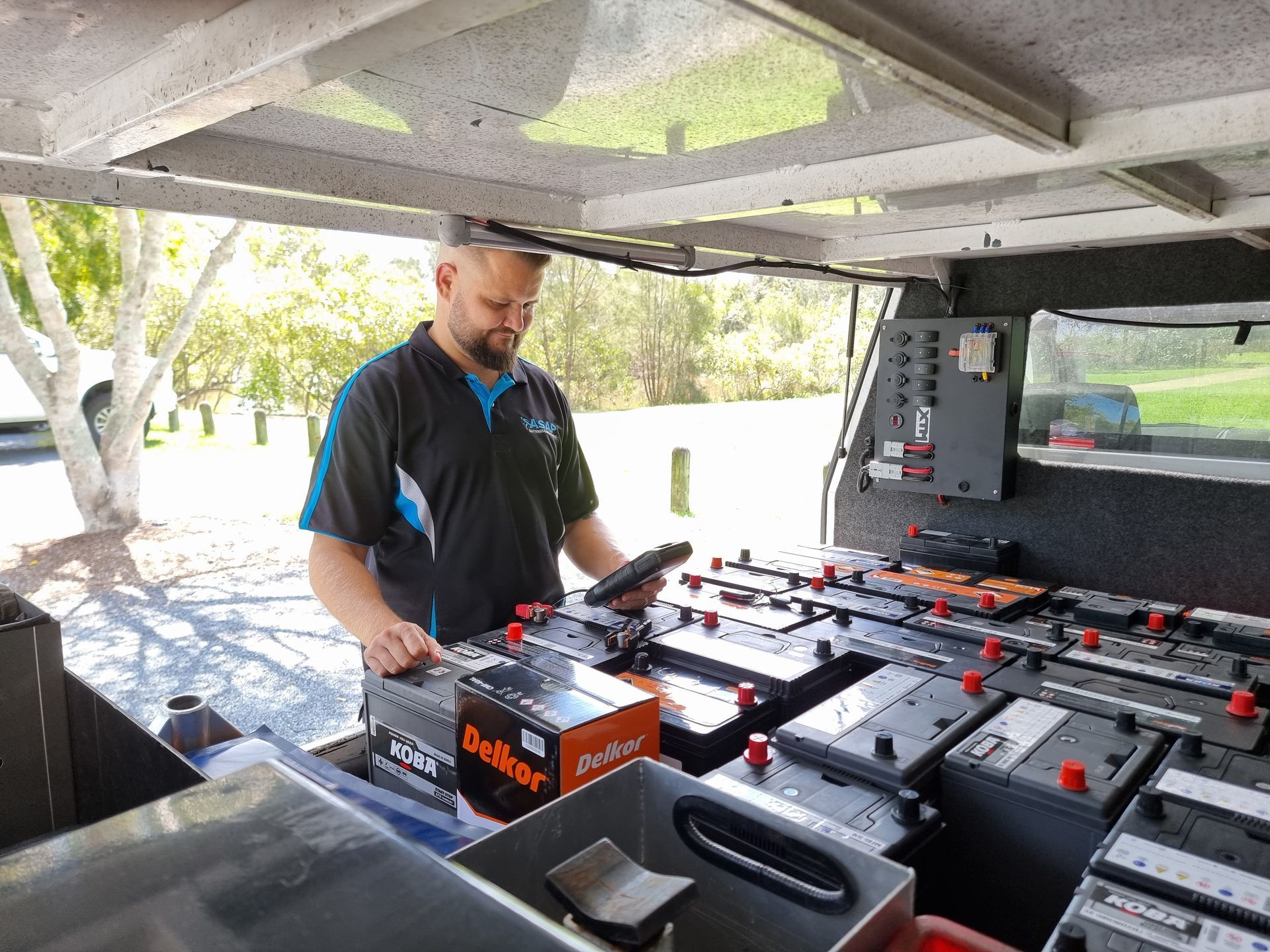 Man in a Utility Vehicle Inspecting Batterie — ASAP Batteries & Breakdowns in Helensvale, QLD