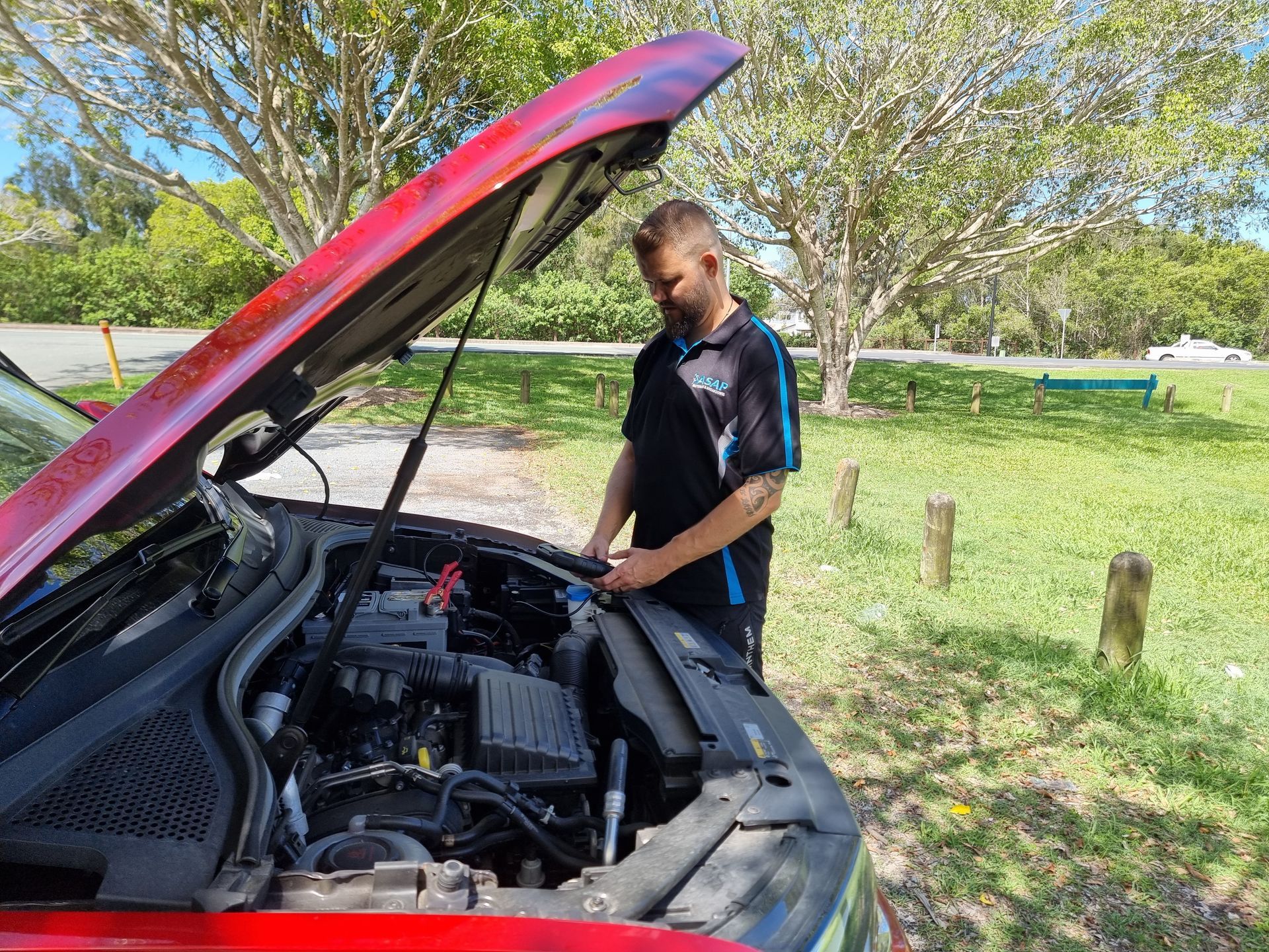 A Person in a Black Shirt Inspects the Engine of a Red Car — ASAP Batteries & Breakdowns in Tweed Heads, NSW