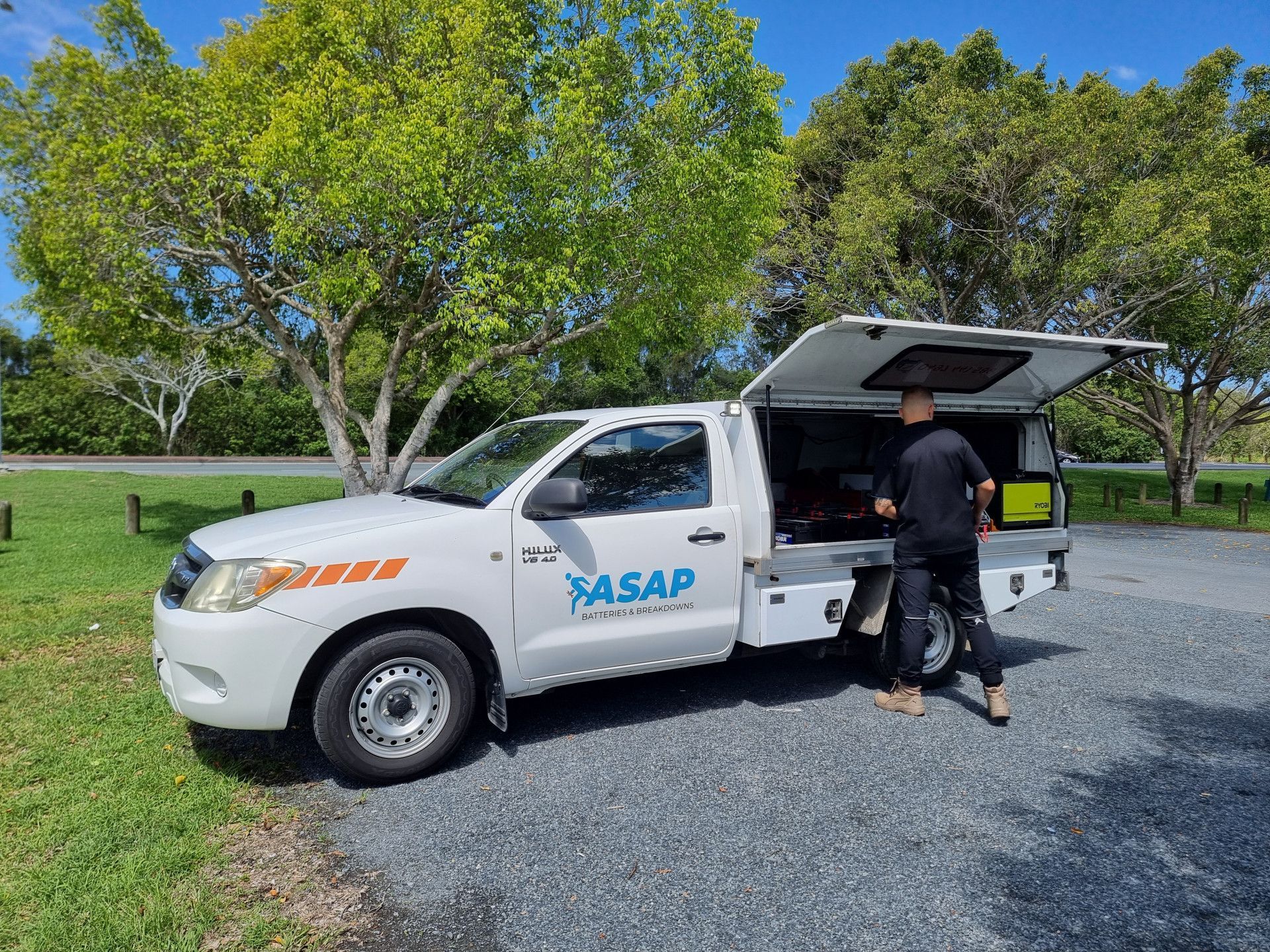 Mobile battery technician working from work ute preparing roadside car battery replacement.