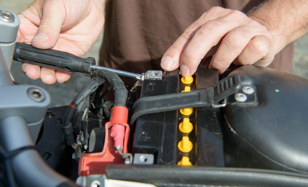 Hands Installing Motorcycle Battery, With Black Battery — ASAP Batteries & Breakdowns in Helensvale, QLD