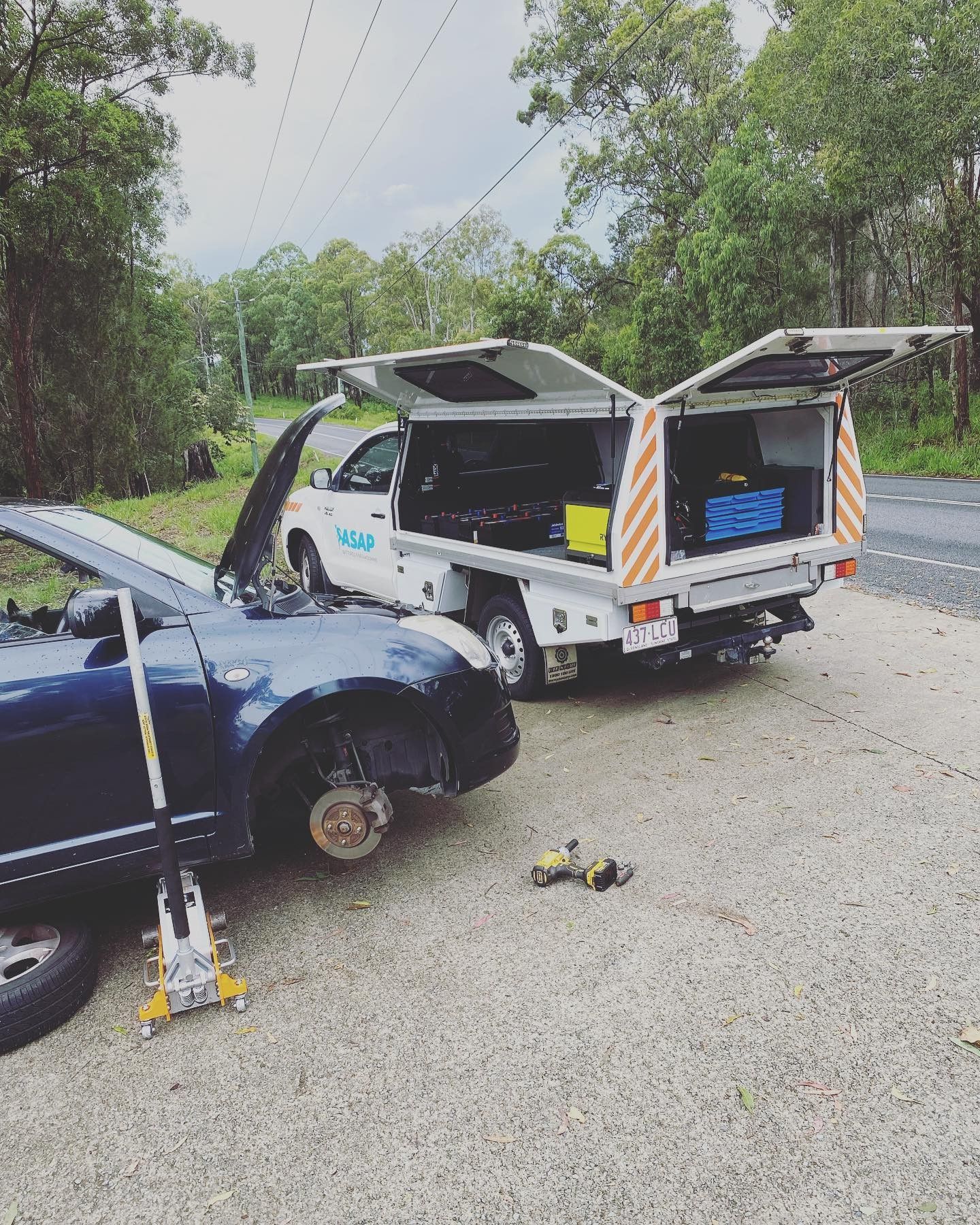 A Blue Car, Missing a Front Wheel and Jacked Up on the Side of a Road — ASAP Batteries & Breakdowns in Southport, QLD