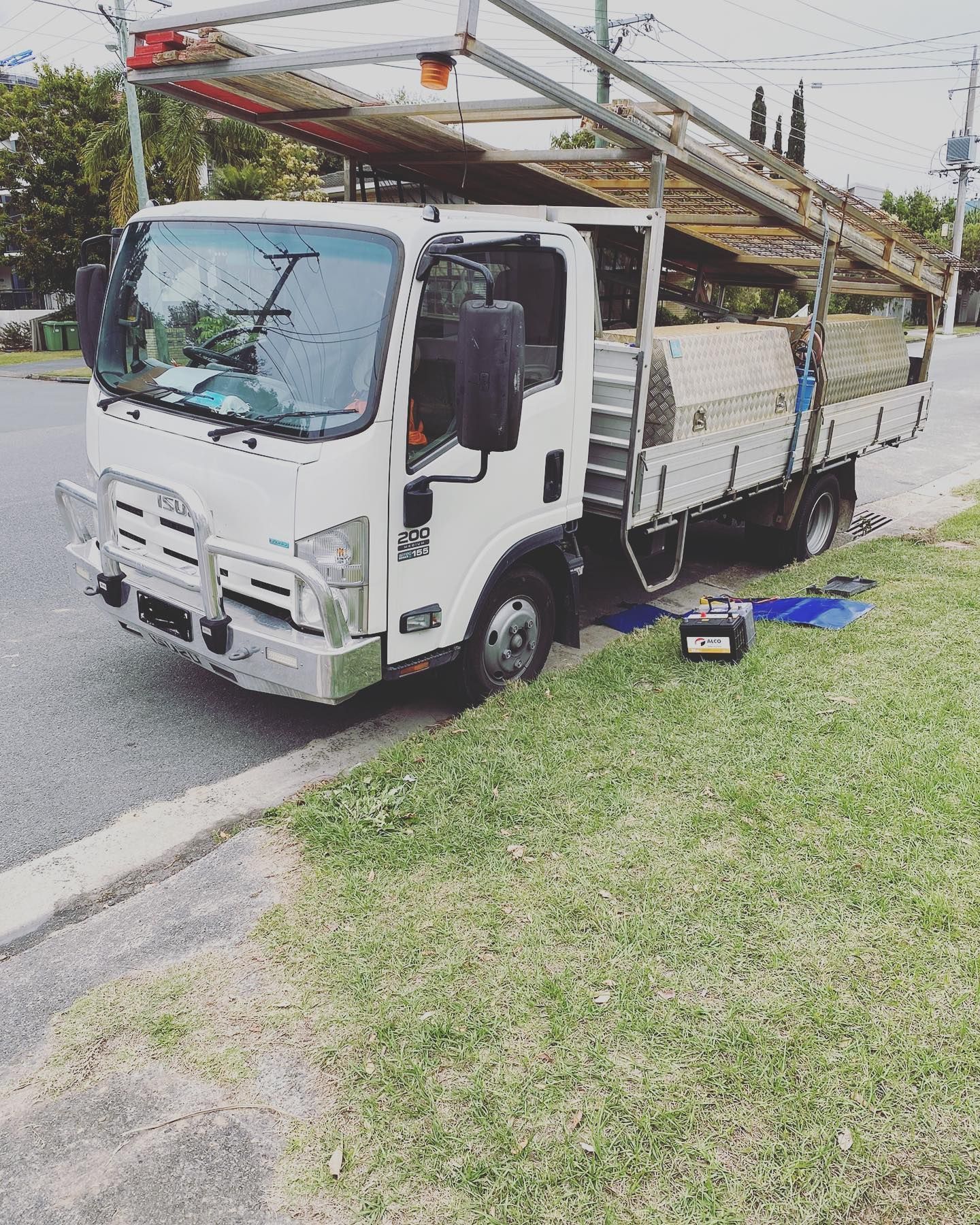 A White Flatbed Truck Parked on a Grass Verge — ASAP Batteries & Breakdowns in Robina, QLD