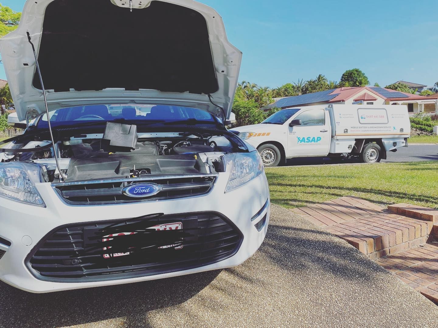 A White Ford Car With Its Hood Up, Parked in a Residential Driveway — ASAP Batteries & Breakdowns in Helensvale, QLD