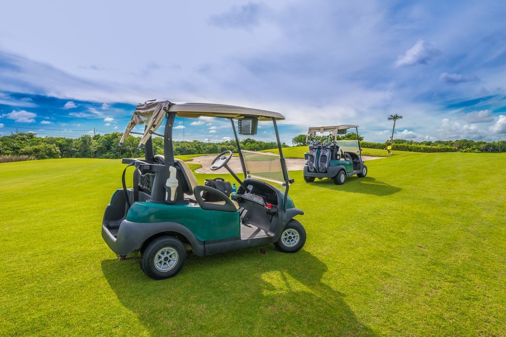 Two Golf Carts on Green Grass, One Teal and One White — ASAP Batteries & Breakdowns in Helensvale, QLD