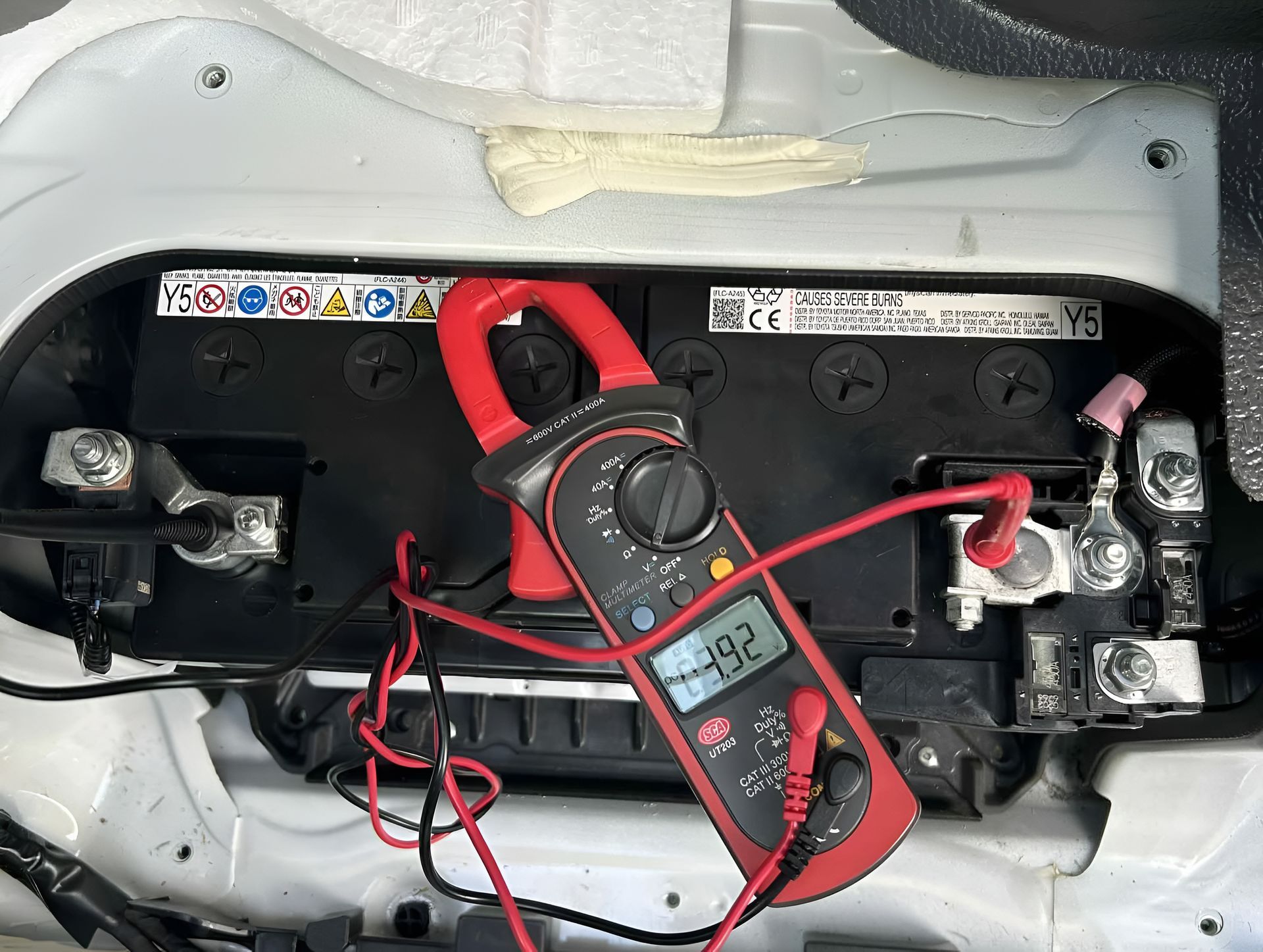 A Multimeter With Red Clamp Leads Attached to a Car Battery — ASAP Batteries & Breakdowns in Southport, QLD
