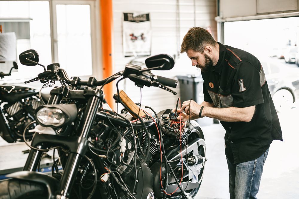 Mechanic Working on the Wiring of a Black Motorcycle — ASAP Batteries & Breakdowns in Helensvale, QLD
