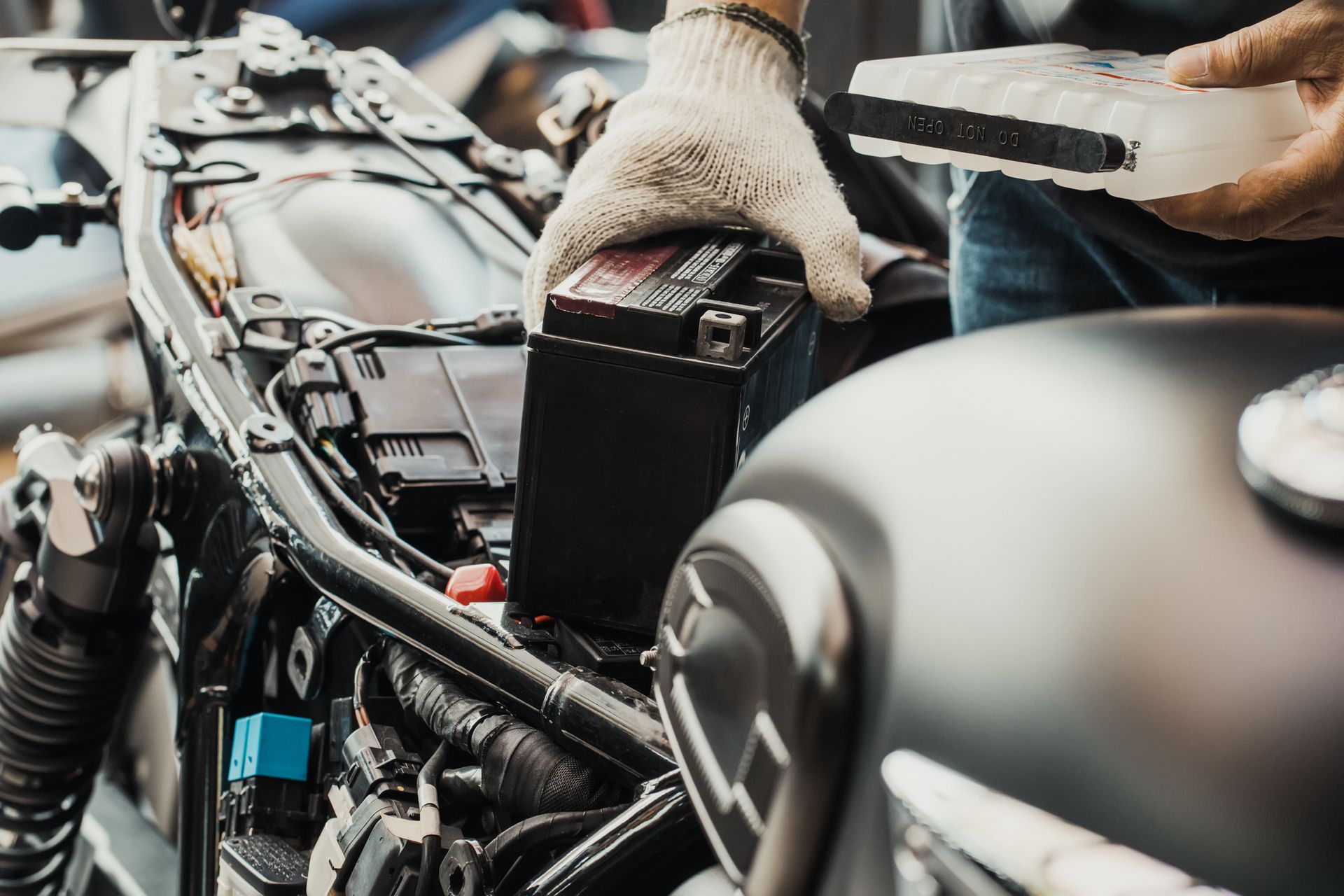 A Person Wearing Work Gloves Installing a Motorcycle Battery — ASAP Batteries & Breakdowns in Coomera, QLD