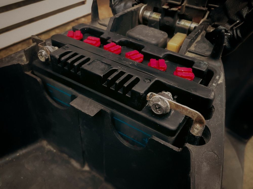 Black Motorcycle Battery in a Compartment, Secured With a Metal Clamp — ASAP Batteries & Breakdowns in Helensvale, QLD