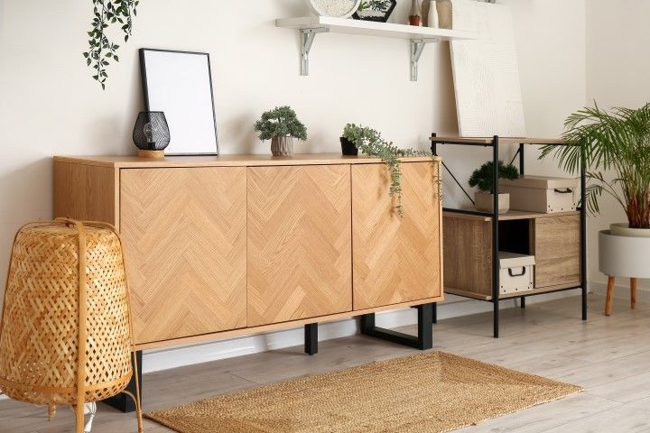 Wooden sideboard and shelving unit in a neutral-toned room, with plants, rug, and lamp.