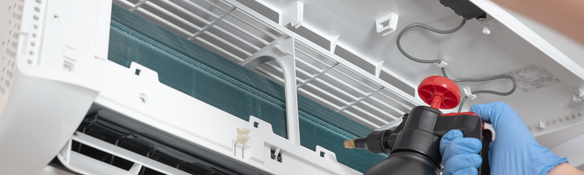 Technician in blue gloves installs a red smoke detector on a white ceiling grid