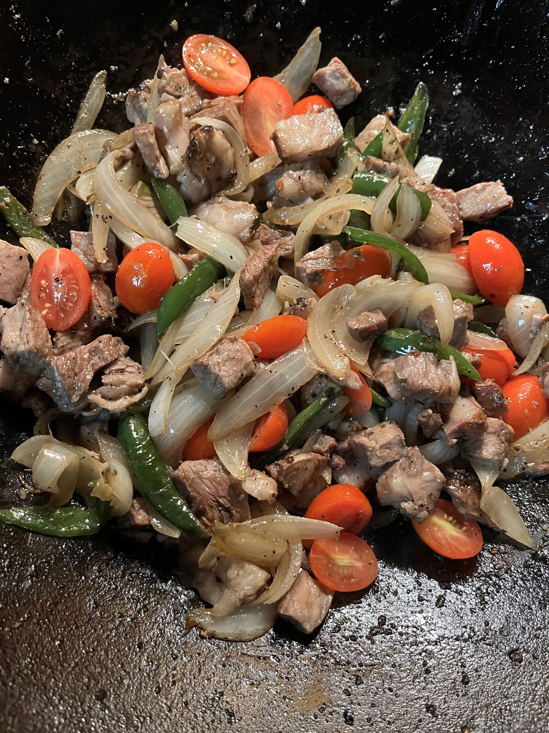 Meat and vegetables are being cooked in a pan