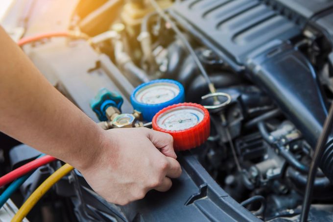 Une personne travaille sur le moteur d’une voiture.