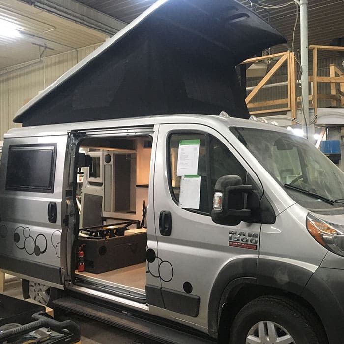 Une camionnette argentée avec un toit noir est garée dans un garage