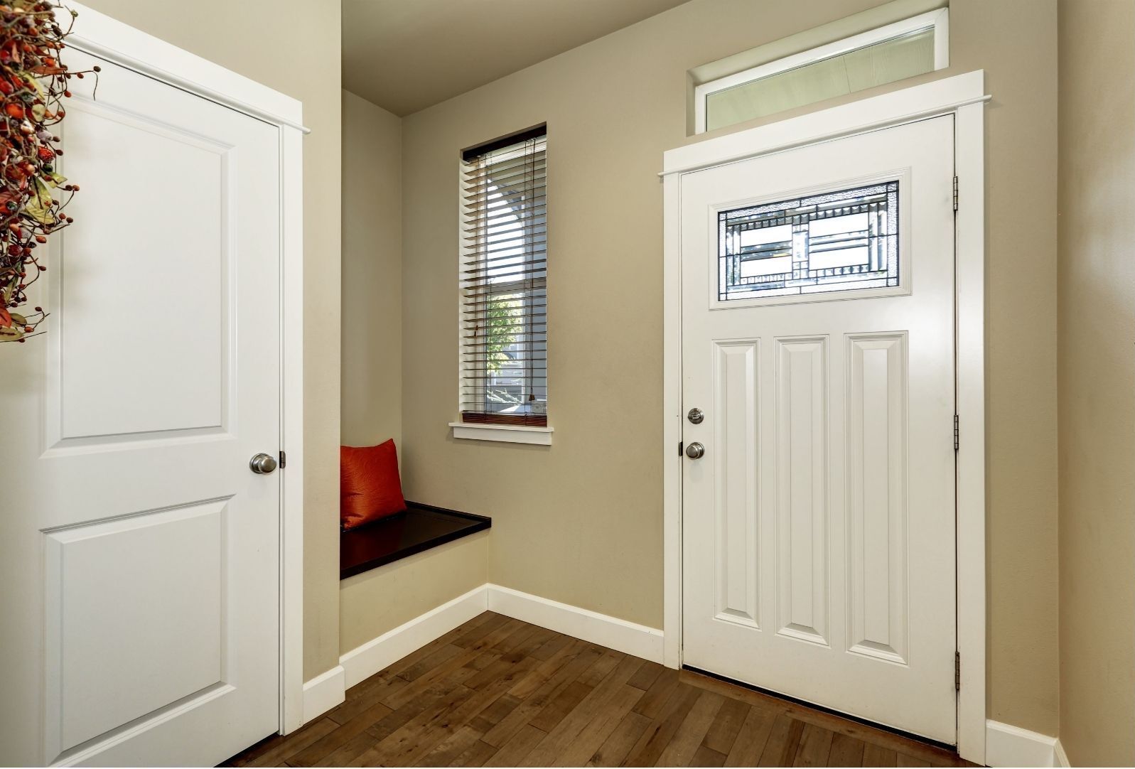 Small entryway with white doors, a window seat, and wood flooring