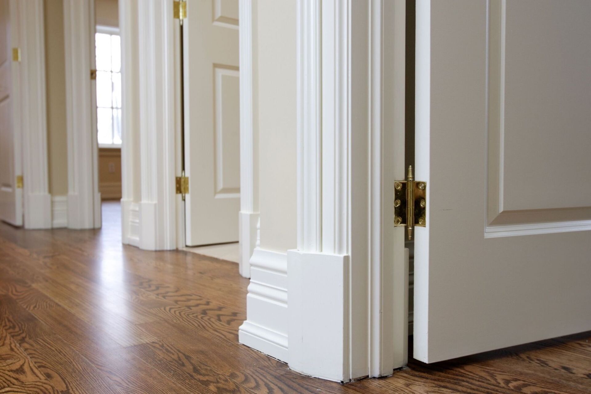 Bright hallway with wood floors, white walls, and open doors