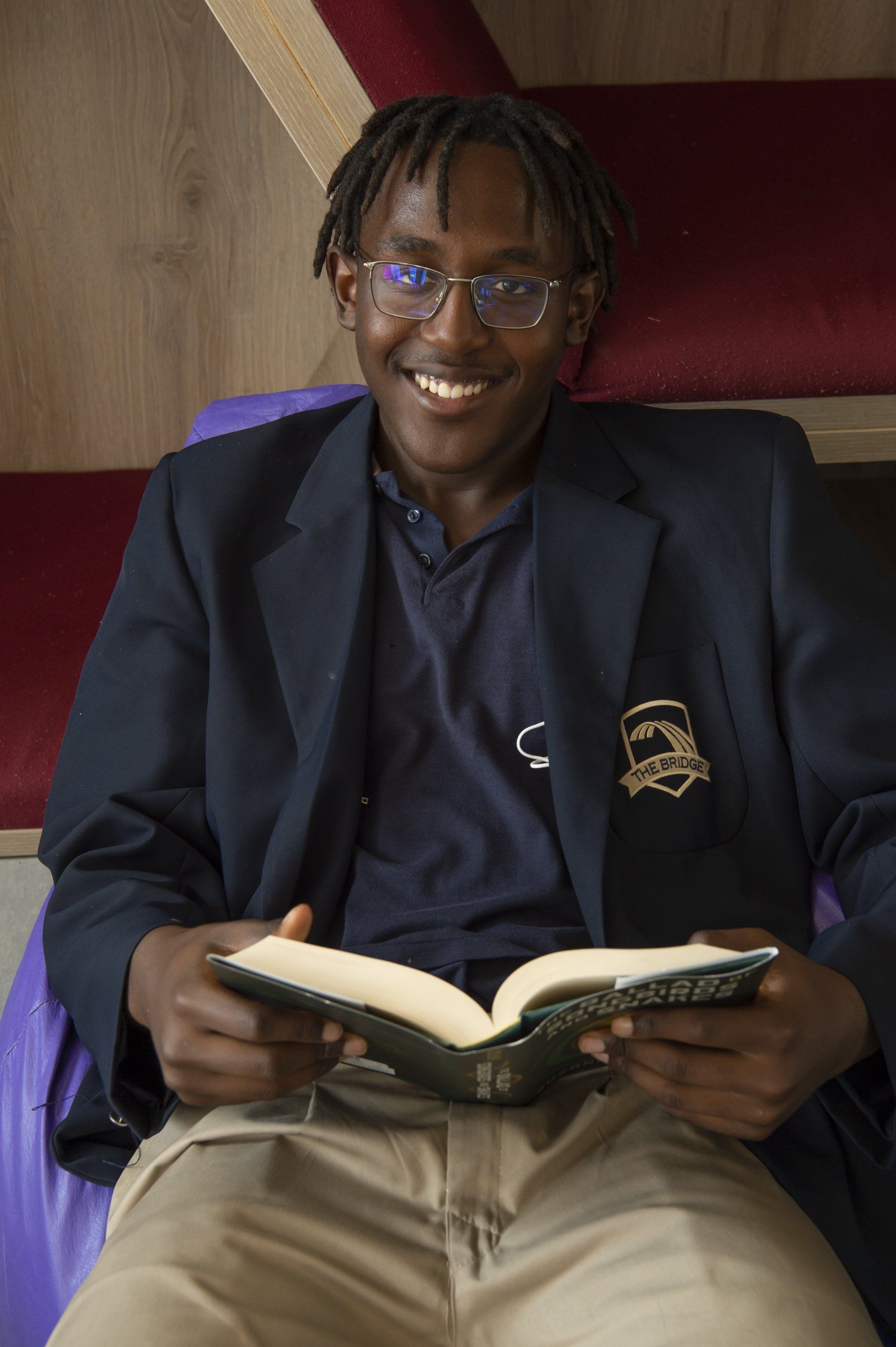 a young man is sitting on a bean bag chair reading a book .