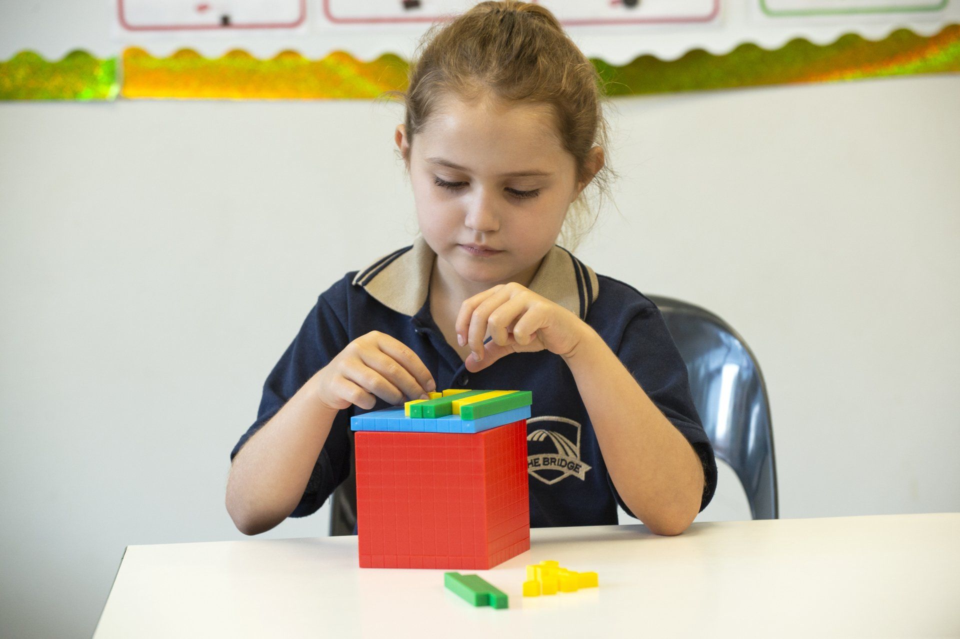 A young girl is sitting at a table playing with blocks.