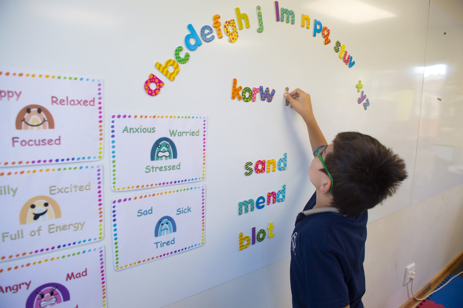 a young boy is writing on a whiteboard in a classroom .