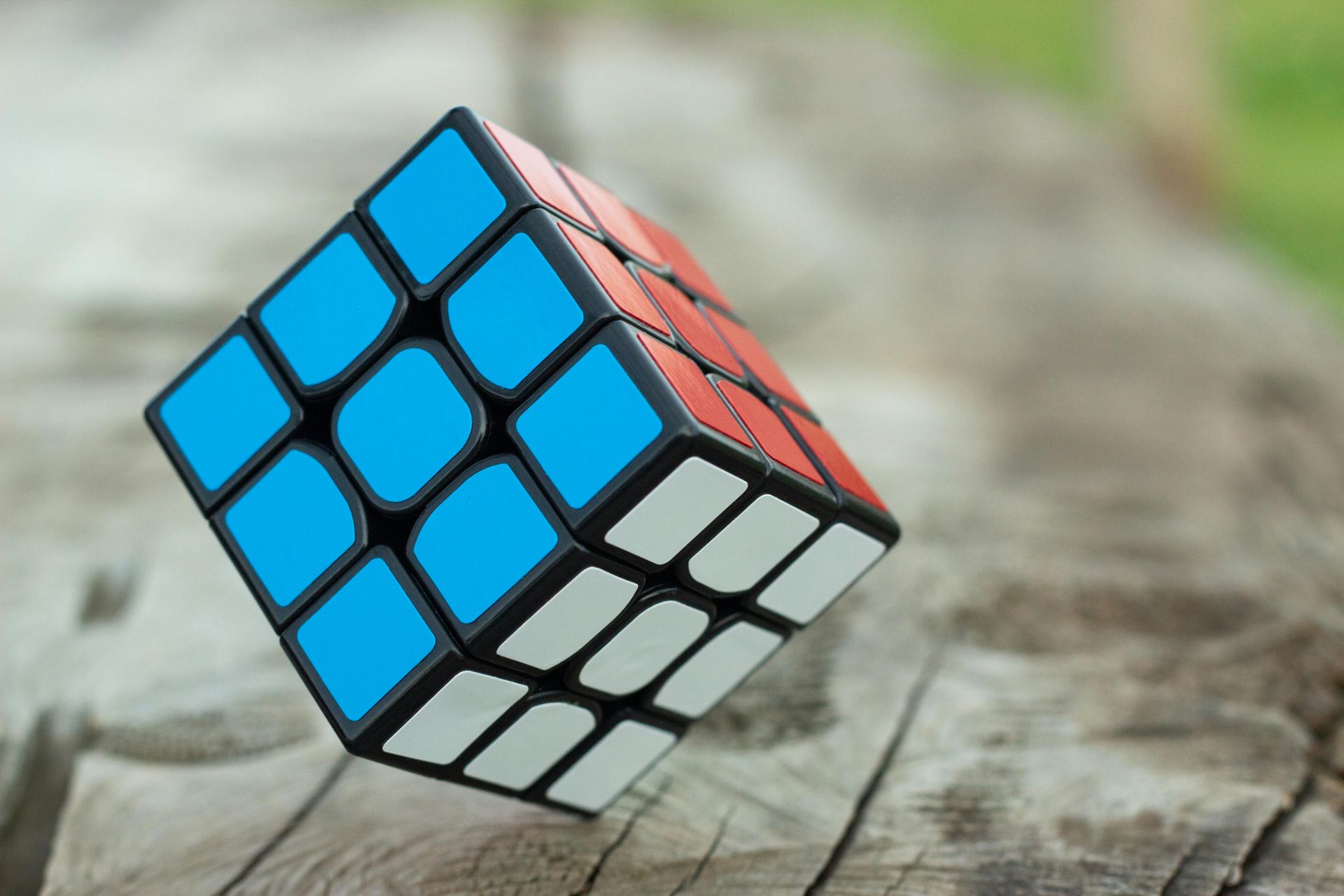 A Rubik's cube, with blue, orange, and white sides, sitting on a wooden surface.