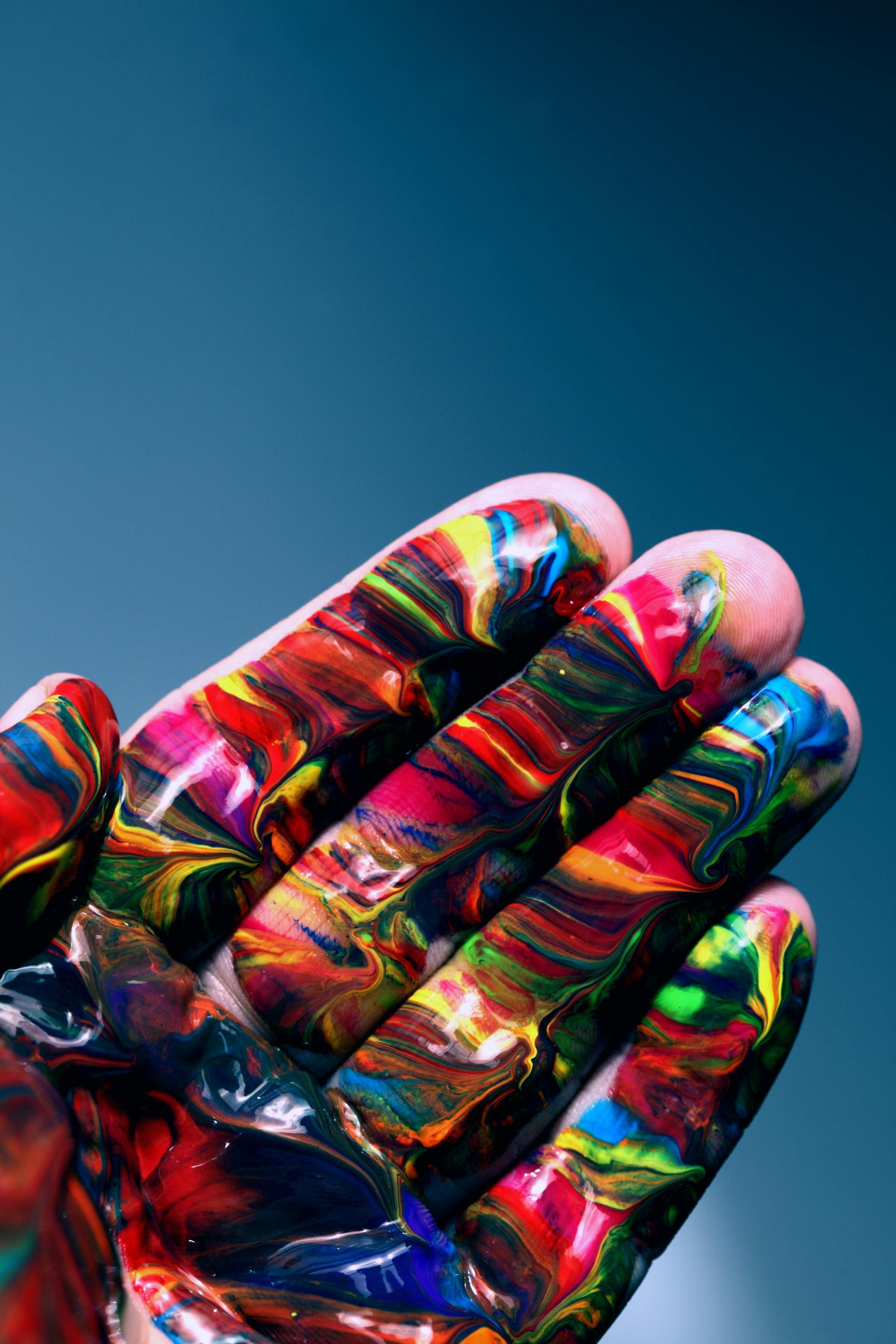A close up of a person 's hand covered in colorful paint.