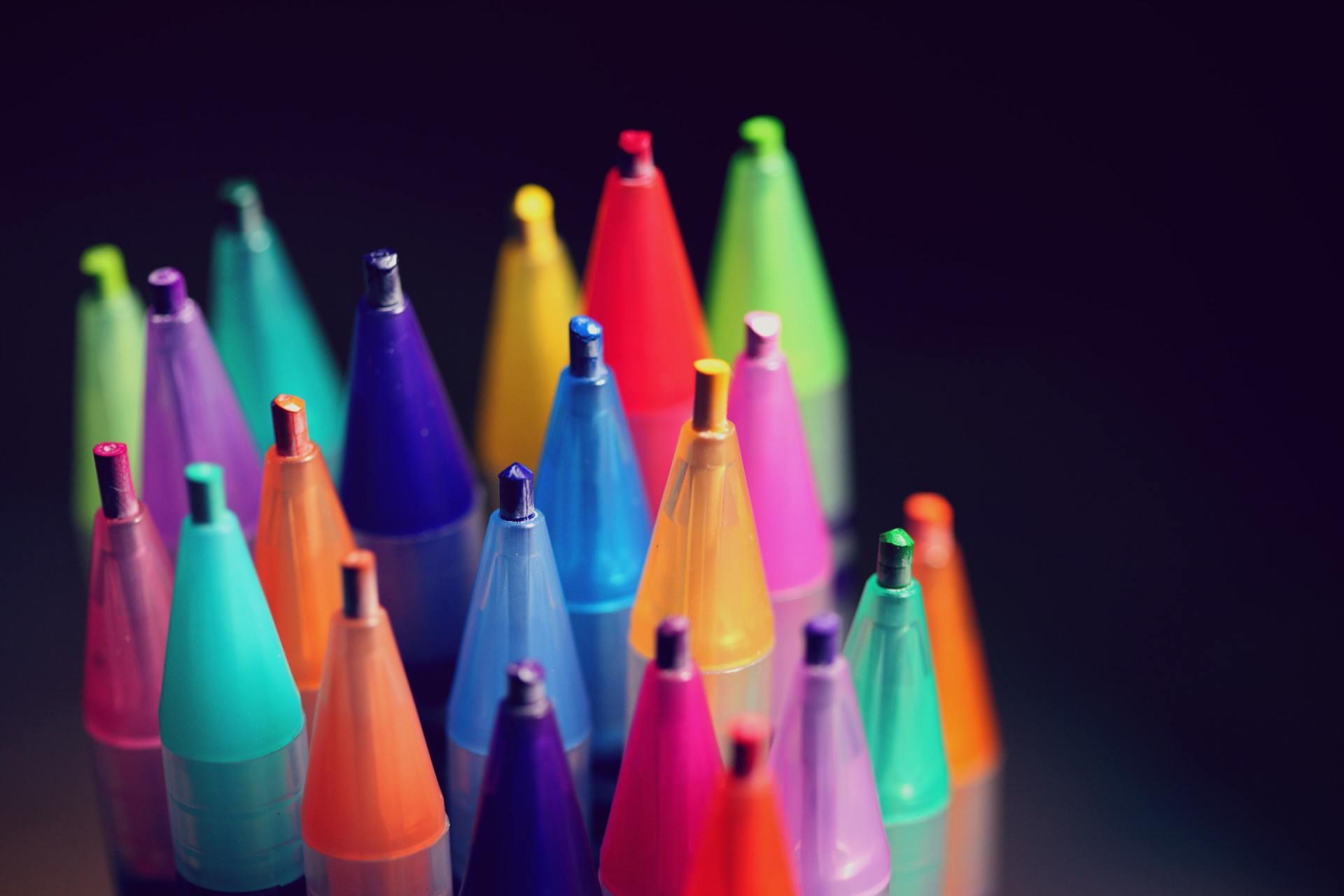 A bunch of colorful pens are sitting on top of each other on a table.