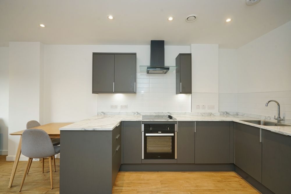 Modern white kitchen with dark cabinets, island, wood floor, and dining table by the window